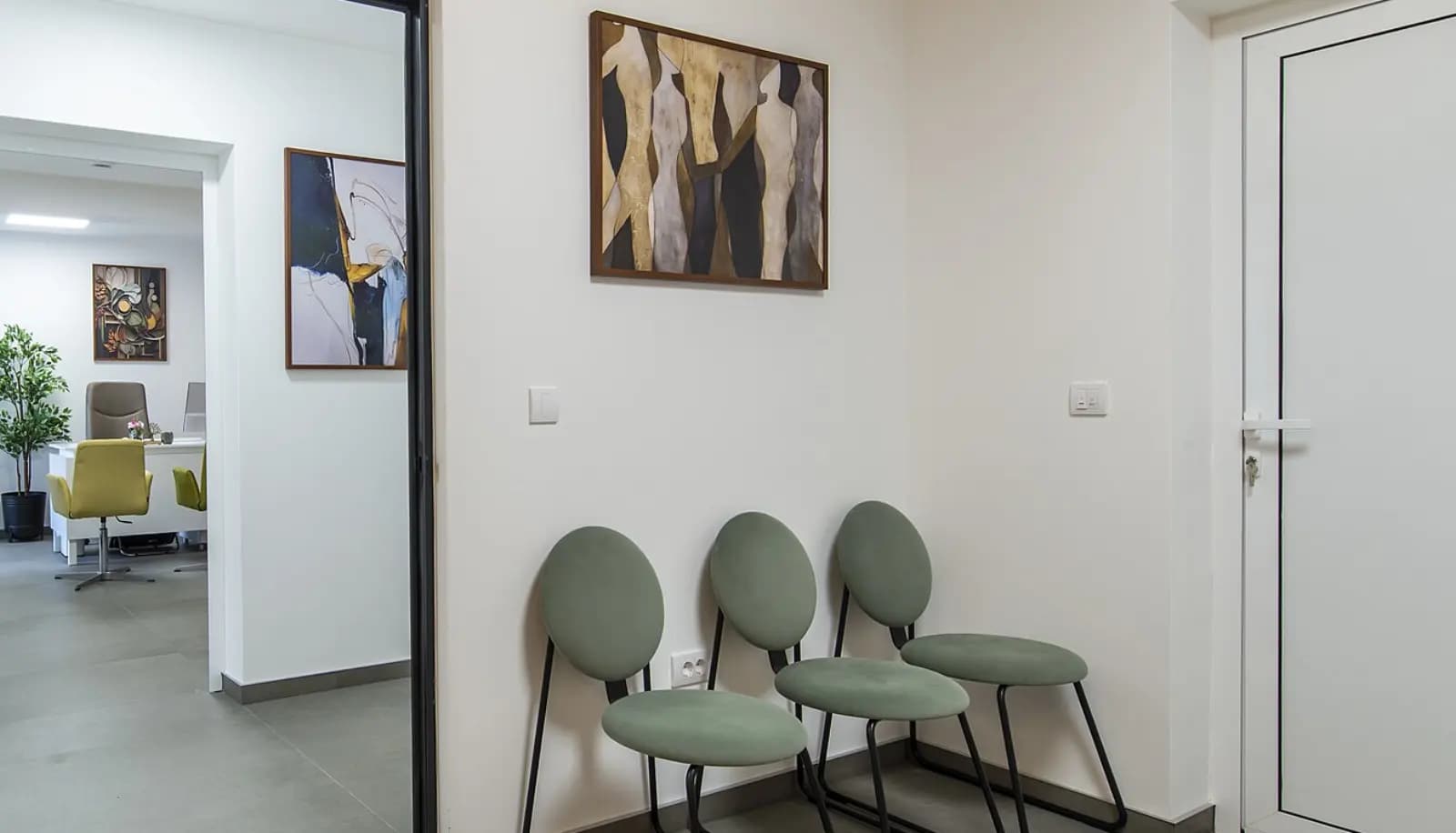 Le coin d’attente du cabinet, trois chaises et la porte ouverte sur la salle de consultation