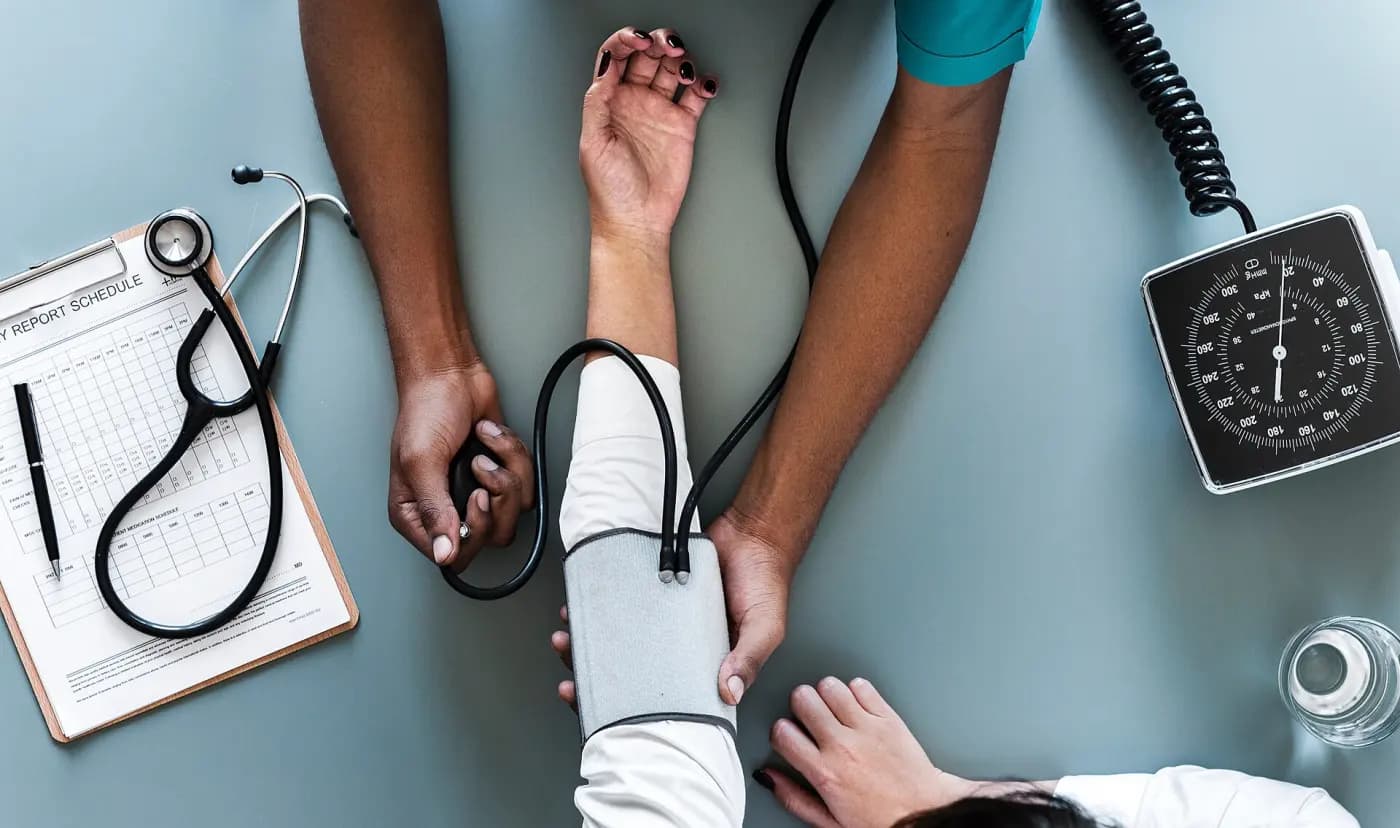 Une prise de tension au brassard, avec le stéthoscope et la fiche de suivi